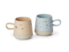 Two ceramic mugs with speckled patterns on a white background
