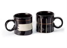 Two black mugs with white interior designs on a white background