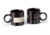 Two black mugs with white interior designs on a white background