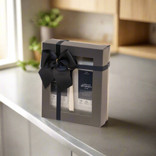 Gift box with two bottles and a black bow on a kitchen counter