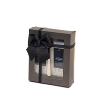A gift tray containing two packets of black tea leaves, one labeled Assam Mokalbari and the other Ceylon OP UVA Badulla, tied with a navy blue ribbon.