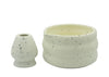 Two ceramic containers with speckled texture on a light gray background
