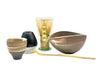 Set of Japanese tea-making tools including cups, a whisk, and a scoop on a white background