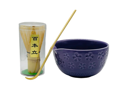 Purple ceramic bowl with a wooden spoon and a transparent container with matcha sticks on a gray background