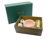 Gift set with a pink bowl, bottle, and other items in a box on a white background