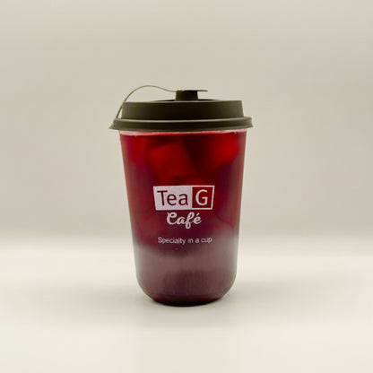 A reusable plastic takeaway cup filled with a dark red beverage, featuring a black lid with a carry loop and the white printed logo 'Tea G Cafe' on the front, set against a plain light gray background.